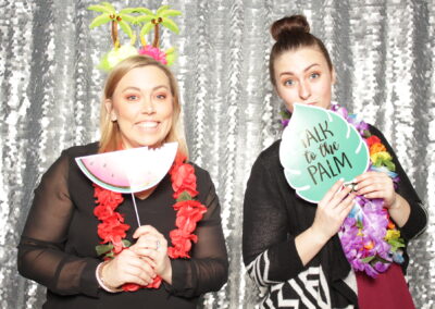 Two women posing with fun tropical photo booth props.